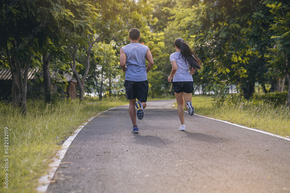 Fototapeta premium Silhouette of young couple running together on road. Couple, fit runners fitness runners during outdoor workout with sunset background.