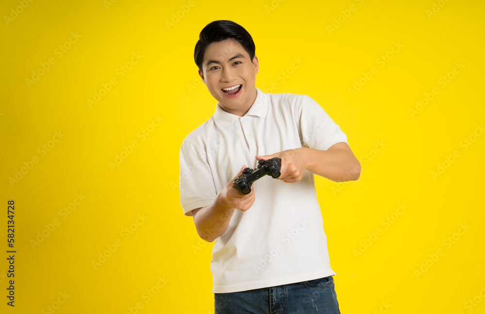 Portrait of young asianman playing game on yellow background Portrait of young asianman playing game on yellow background
