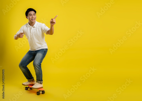 image of young asian male playing skateboard on a yellow background