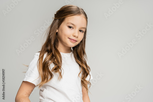 Preteen child in white t-shirt looking at camera isolated on grey.