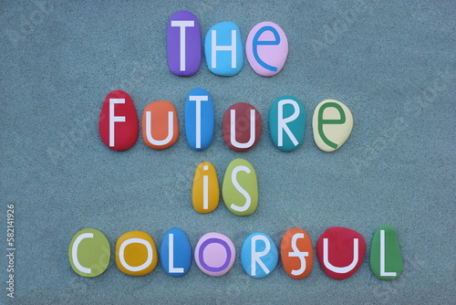 The future is colorful, creative message composed with hand painted multi colored stone letters over green sand