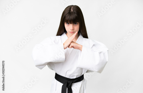 Little caucasian girl over isolated white background doing karate and saluting photo