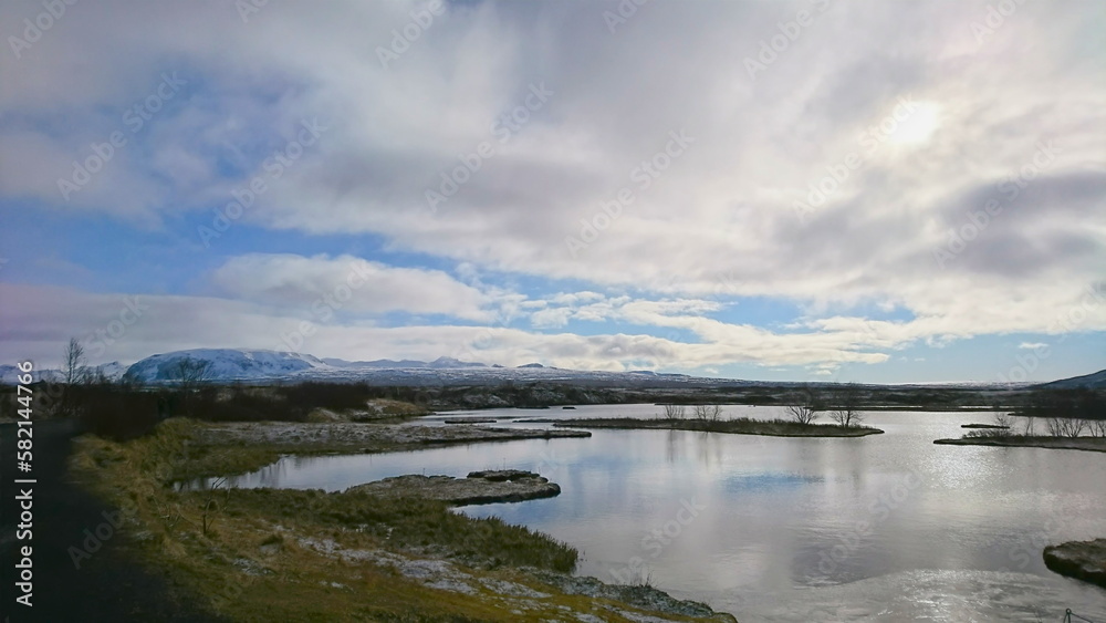 Thingvellir National Park, Iceland - March 24, 2018: frozen lake with a snow-capped mountain in the back under a cloudy blue sky