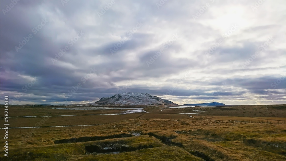Skalholt, Iceland - March 24, 2018: looking at a lonely snow-capped mountain under a cloudy sky