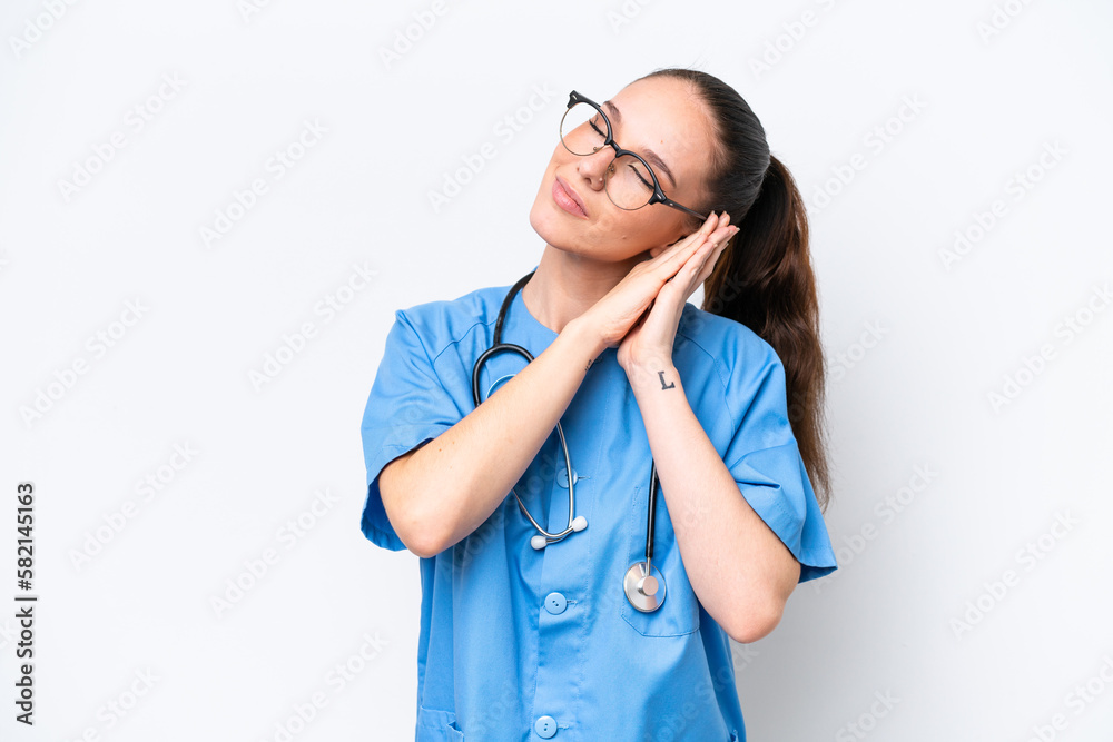 Young caucasian surgeon doctor woman isolated on white background making sleep gesture in dorable expression Young caucasian surgeon doctor woman isolated on white background making sleep gesture in dorable expression