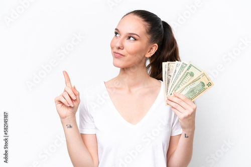 Young caucasian woman taking a lot of money isolated on white background pointing up a great idea