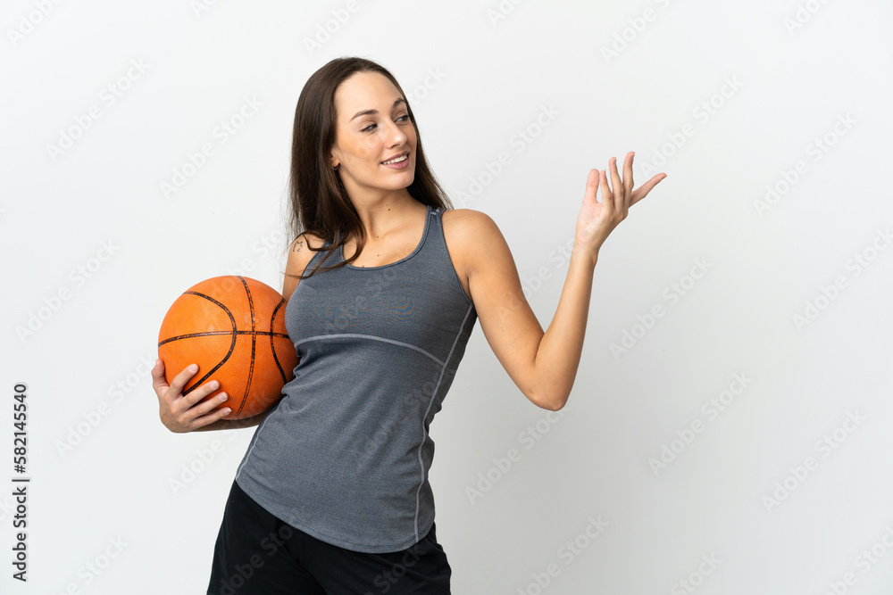 Young woman playing basketball over isolated white background extending hands to the side for inviting to come