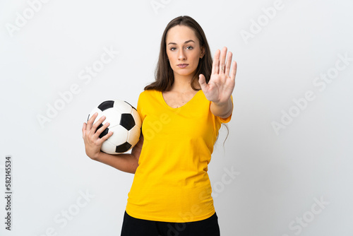 Young football player woman over isolated white background making stop gesture © luismolinero