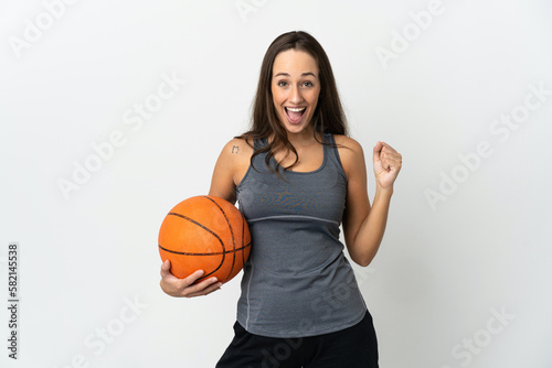 Young woman playing basketball over isolated white background celebrating a victory in winner position