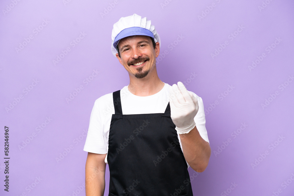 Fishmonger man wearing an apron isolated on purple background inviting to come with hand. Happy that you came Fishmonger man wearing an apron isolated on purple background inviting to come with hand. Happy that you came