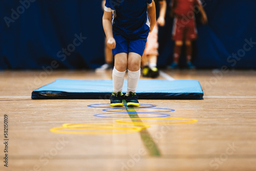 Group of children in school age jumping over obstacles at indoor training drill photo