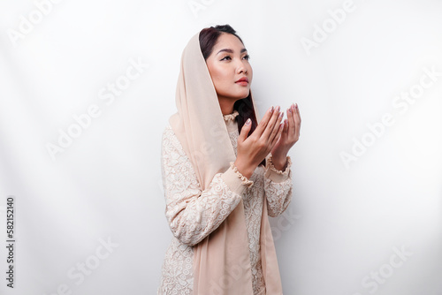 Religious beautiful Asian Muslim girl wearing a headscarf praying to God. photo