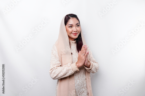 Portrait of a young beautiful Asian Muslim woman wearing a headscarf gesturing Eid Mubarak greeting