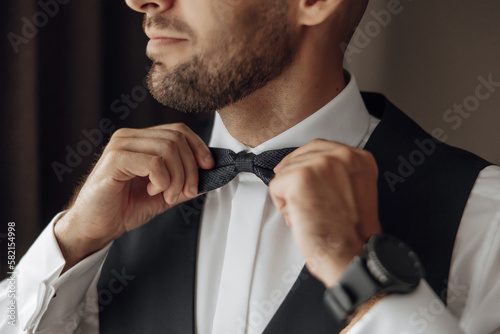 The stylish bridegroom dresses, prepares for the wedding ceremony. The groom's morning. Businessman wears a jacket, male hands closeup, groom getting ready in the morning before wedding ceremony photo