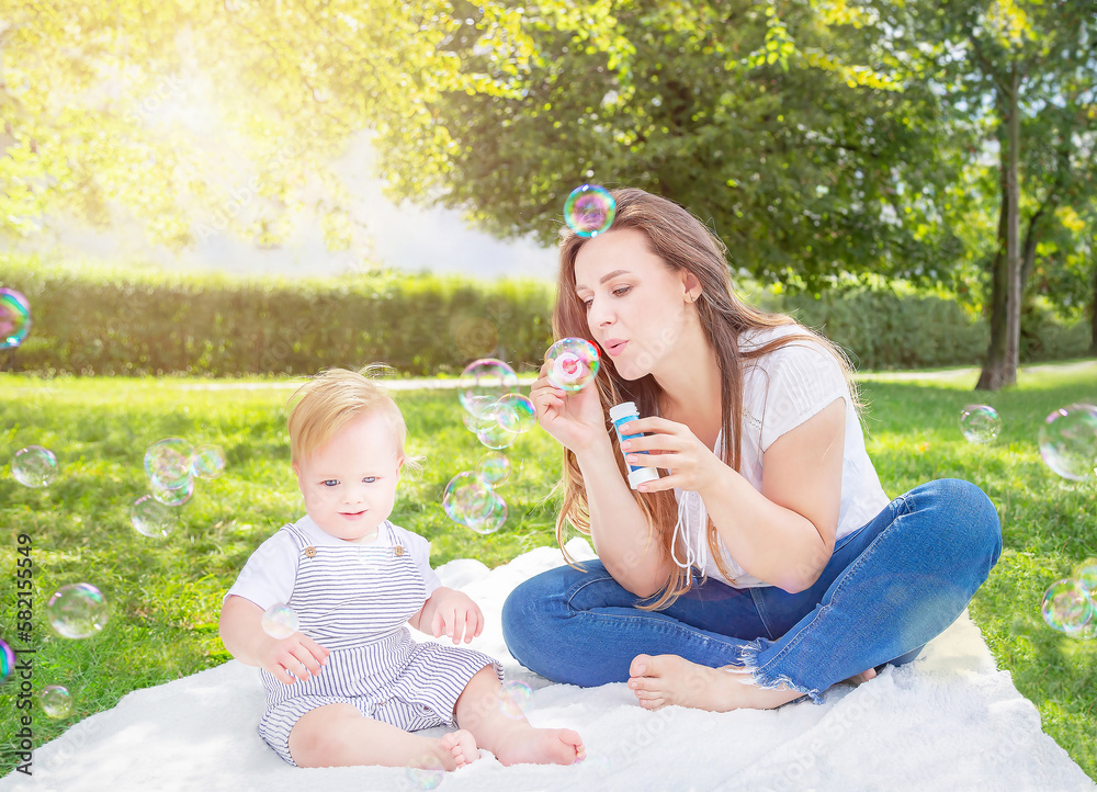 Healthy child (kid) having fun with mother and soap bubbles in a sunny summer day at the park. Caucasians happy baby (boy) in the casuals clothing. Healthy lifestyle, family, childhood, Mother's Day. Healthy child (kid) having fun with mother and soap bubbles in a sunny summer day at the park. Caucasians happy baby (boy) in the casuals clothing. Healthy lifestyle, family, childhood, Mother's Day.