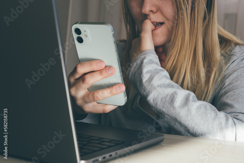 Cropped portrait of female blogger biting fingers nervous using mobile phone. Panic, shock, bulling concept. High quality toned photo about technology and security.  photo