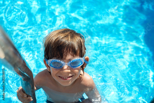 Boy on the pool ladder with aqua goggles
