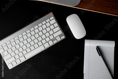 Office table around the keyboard, mouse, notepad and pen on the black background photo