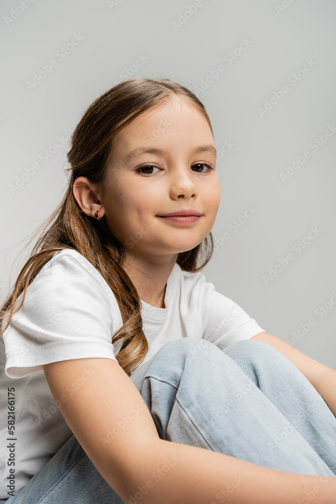 Portrait of smiling preteen girl in jeans and t-shirt looking at camera isolated on grey. Portrait of smiling preteen girl in jeans and t-shirt looking at camera isolated on grey.