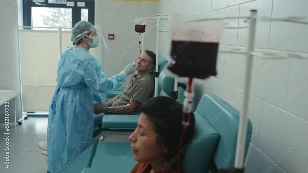 Selective focus shot of unrecognizable medical worker checking process of blood drawing from donors Selective focus shot of unrecognizable medical worker checking process of blood drawing from donors