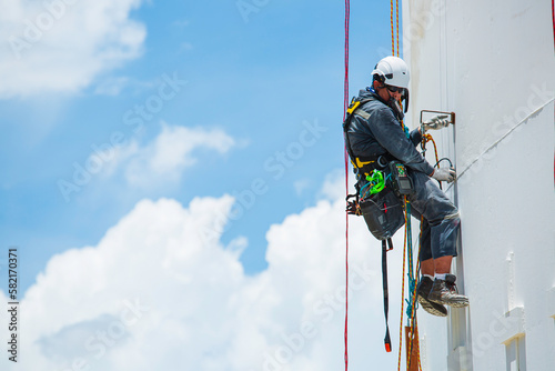 Male worker down height tank roof rope access safety inspection thickness weld of storage tank.