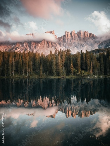 Valokuva Vertical shot of a lake surrounded by a forest and Italian dolomites during the