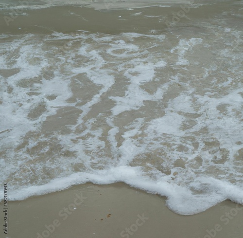 Image of bubbly white waves in the movement on the beach