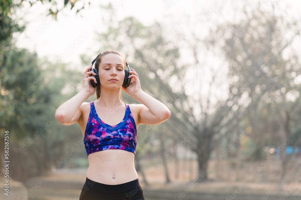 A relaxed woman is shown enjoying music while jogging through a public park. The young lady is feeling free, relaxed, and happy. A relaxed woman is shown enjoying music while jogging through a public park. The young lady is feeling free, relaxed, and happy.