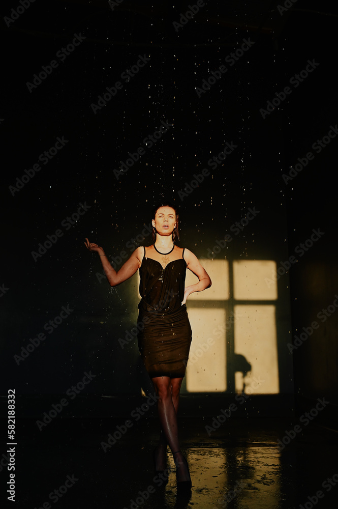 Water splash. A girl in black dress under the drops water. Wet clothes. Young woman enjoying relaxed. Water splash. A girl in black dress under the drops water. Wet clothes. Young woman enjoying relaxed.