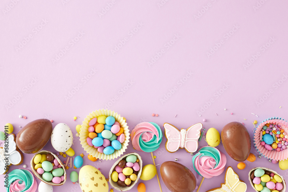 Easter sweets concept. Top view photo of chocolate eggs paper baking molds with dragees meringue lollipops sprinkles and gingerbread on pastel violet background with copyspace