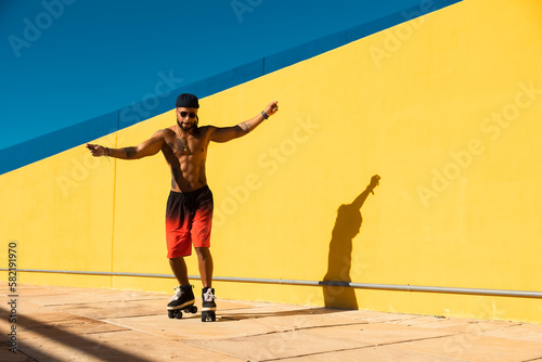 Black man on roller skates riding outside. Urban man posing with roller skates.