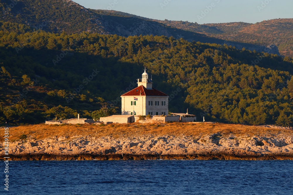 Small lighthouse illuminated by warm sunset light, near island Hvar, Croatia. Small lighthouse illuminated by warm sunset light, near island Hvar, Croatia.