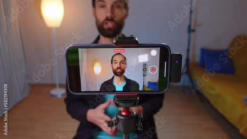 A young bloger records a video with himself on smartphone in his room studio photo