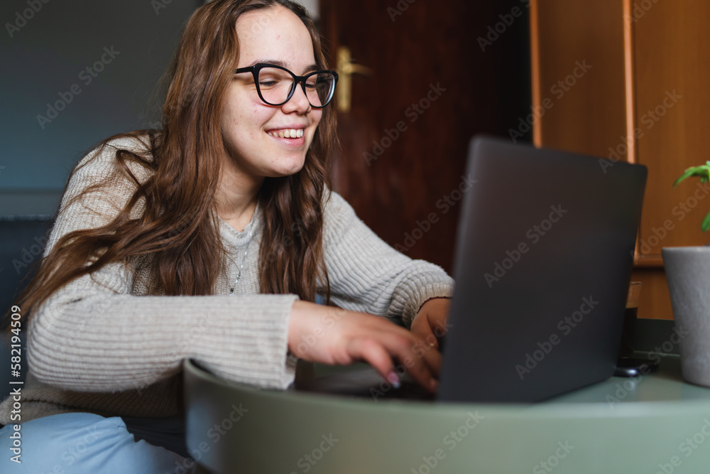 A young girl sitting at home while using laptop to study or do business while drinking coffee and using mobile phone A young girl sitting at home while using laptop to study or do business while drinking coffee and using mobile phone