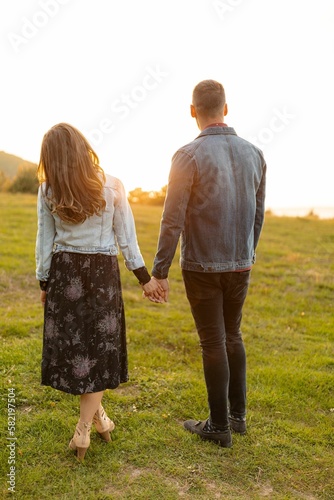 Vertical of a Caucasian couple on green grass, celebrating Valentine's Day at golden hour
