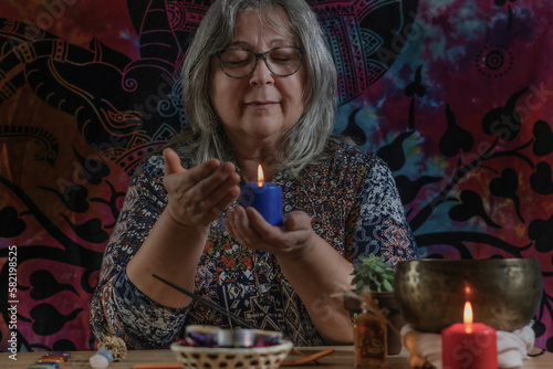 Elderly white-haired woman holding a lighted candle with colorful clothes