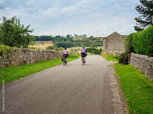 Beautiful shot of two cyclists riding along a country lane in Derbyshire, United Kingdom