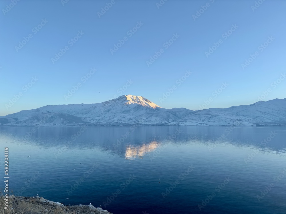 a large body of water surrounded by snow covered mountains in the distance
