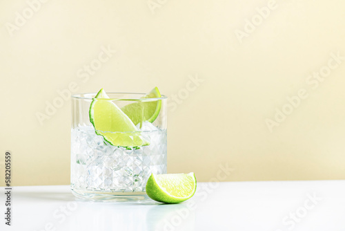 Ti punch alcoholic cocktail drink with white rum agricole, sugar syrup and lime, traditional Caribbean beverage. Beige background, minimalist style photo