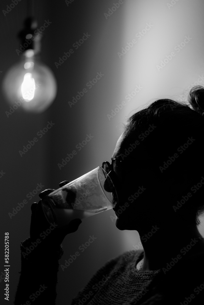Vertical grayscale shot of a female drinking from a glass