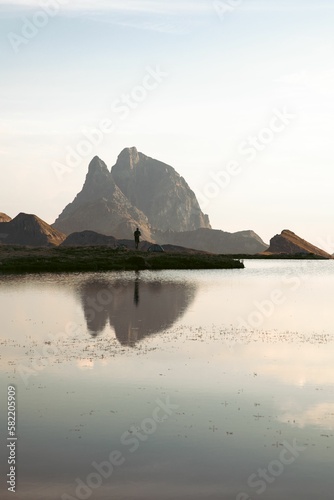 Vertical shot of Pic du Midi d'Ossau mountain peak with reflection on a lake at sunset