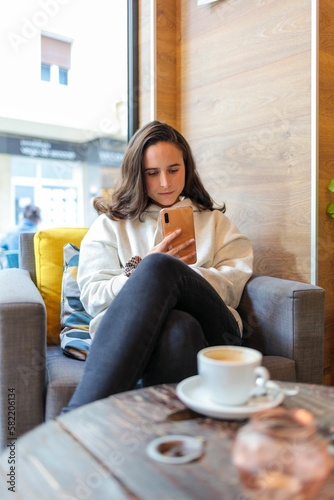 Vertical shot of a Caucasian female sitting in a cafe on her phone