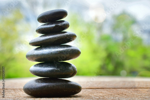 Spa Relaxation Zen concept - cairn, stacked massage therapy stones outside with blurred background.