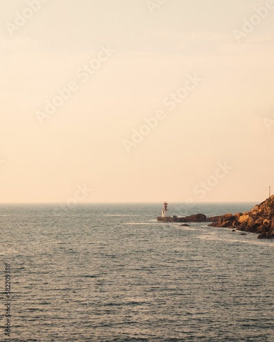 Lighthosue, shore and horiozn of the sea at susnet, vertical