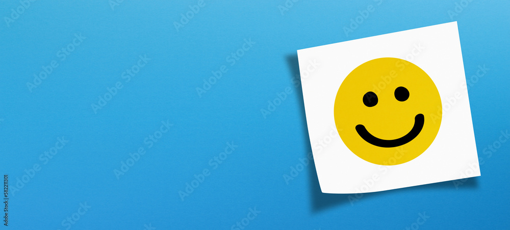 Happy smiley face emoticon with white note paper on blue background - obrazy, fototapety, plakaty 