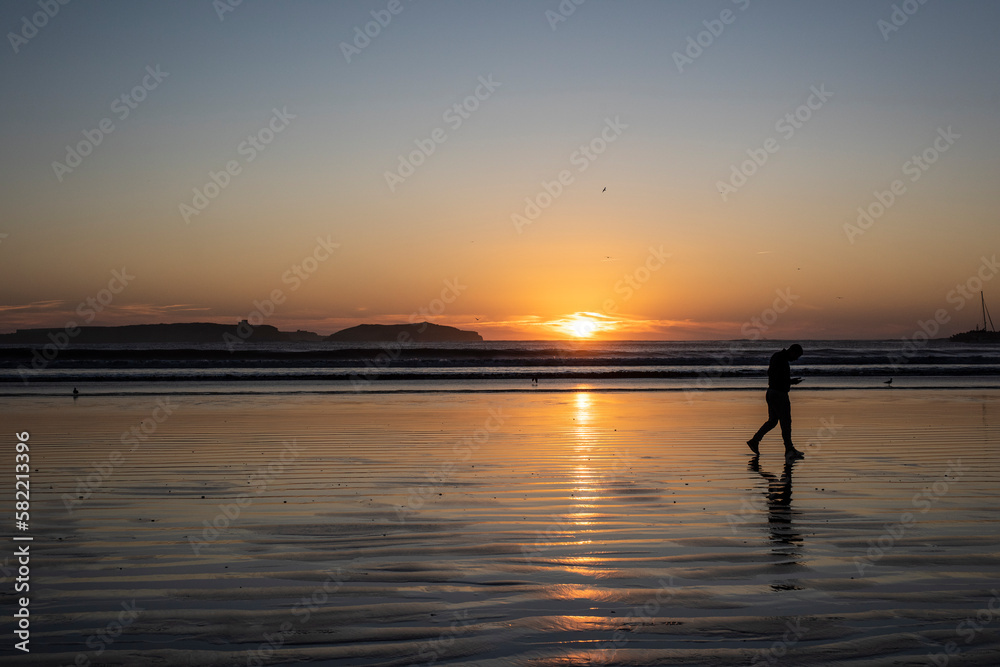 Man walking at sunset on the beach