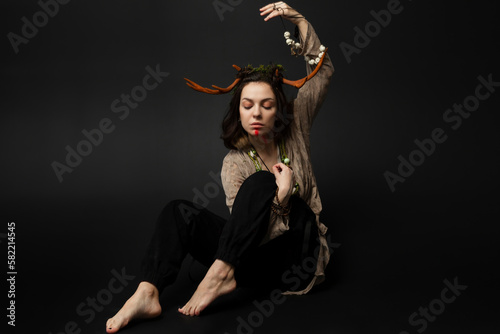 A portrait of a female druid or shaman with horns, holding ritual talismans in her hands on a black isolated background.Shamanic practices,Spiritual rituals,Pagan beliefs,Nature worship,Mystical. photo