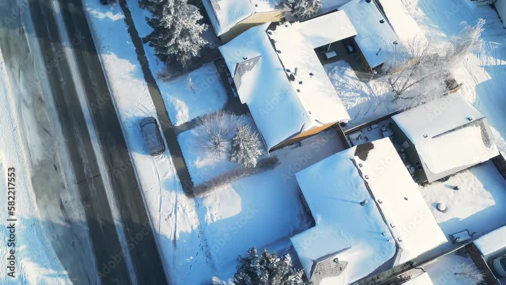 Aerial street view pans up of small neighborhood in the winter time after a snow fall. 