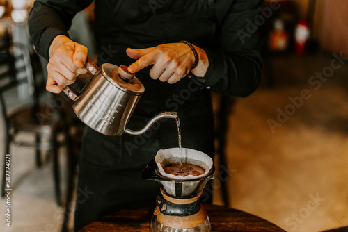Professional barista preparing coffee using chemex pour over coffee maker and drip kettle photo