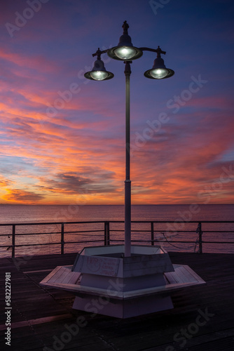 bench on a jetty with lampposts over the mediterranean sea at dawn